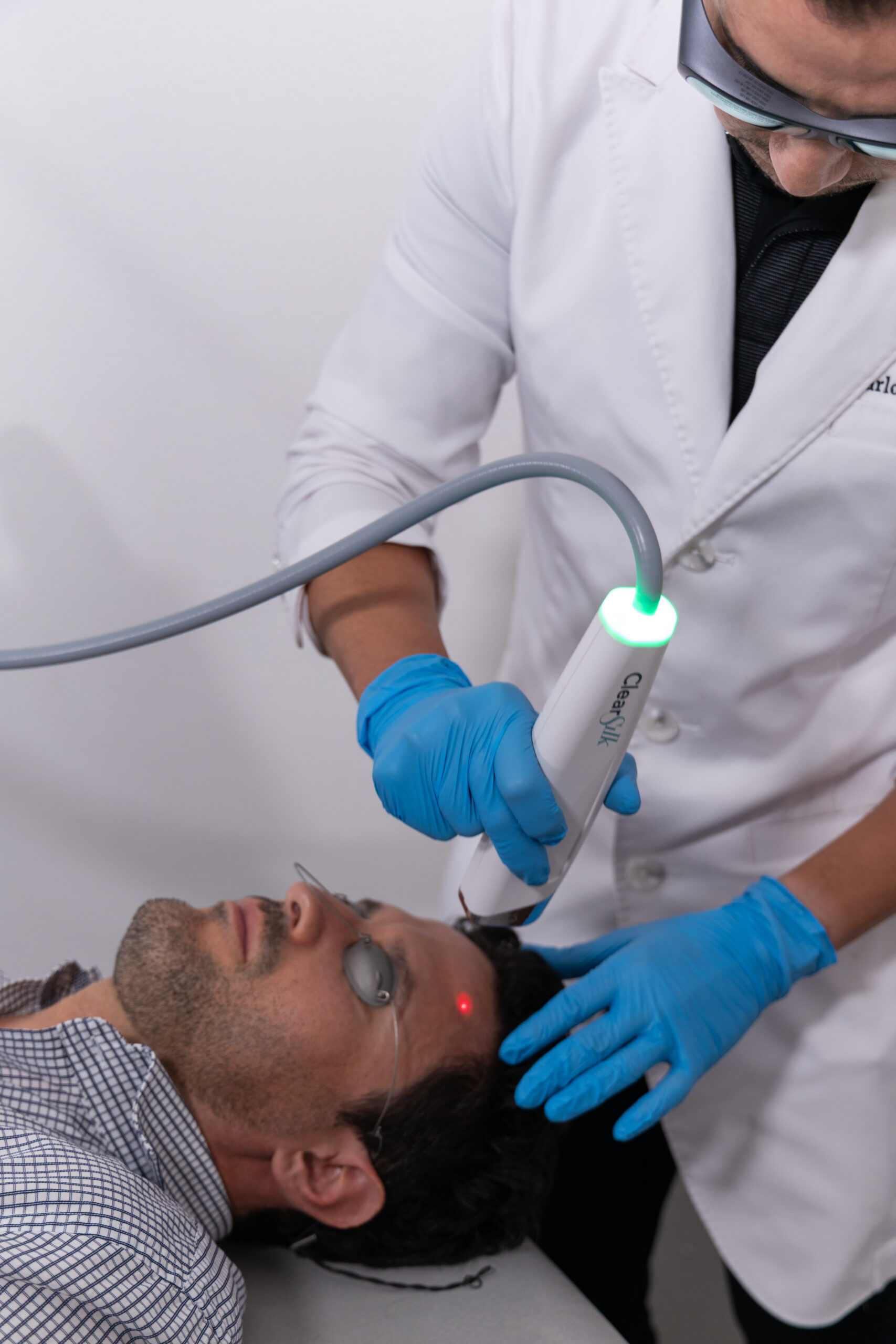 Provider performs a ClearSilk laser facial on a male patient's lower face using the Sciton handpiece